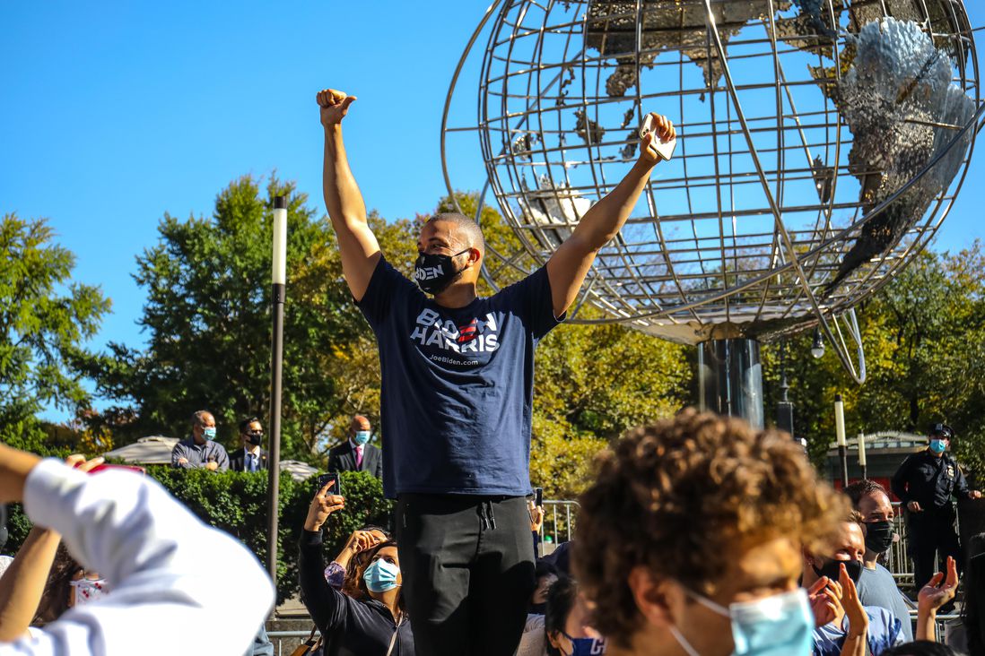 A man wearing a Biden Harris shirt holds up his arms in victory by the Trump International in Columbus Circle